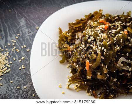 Seaweed Salad With Sesame Seeds Is On A White Plate