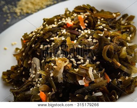Seaweed Salad With Sesame Seeds Is On A White Plate