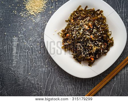 Seaweed Salad With Sesame Seeds Is On A White Plate