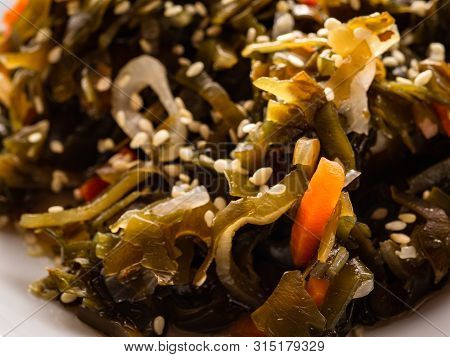 Seaweed Salad With Sesame Seeds Is On A White Plate