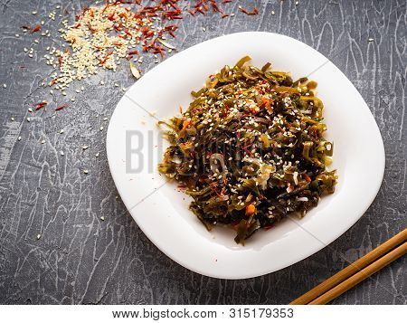 Seaweed Salad With Sesame Seeds Is On A White Plate