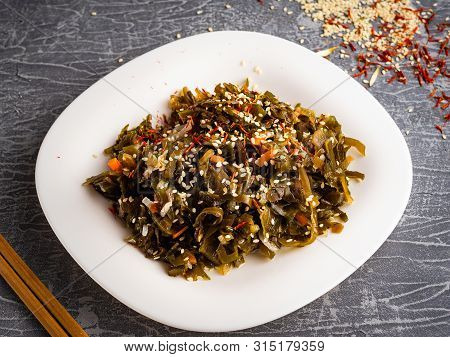 Seaweed Salad With Sesame Seeds Is On A White Plate