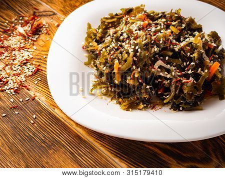 Seaweed Salad With Sesame Seeds Is On A White Plate
