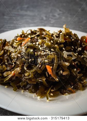 Seaweed Salad With Sesame Seeds Is On A White Plate