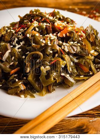 Seaweed Salad With Sesame Seeds Is On A White Plate
