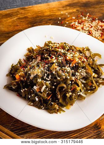 Seaweed Salad With Sesame Seeds Is On A White Plate