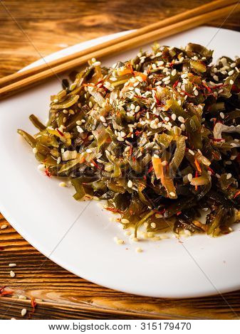 Seaweed Salad With Sesame Seeds Is On A White Plate