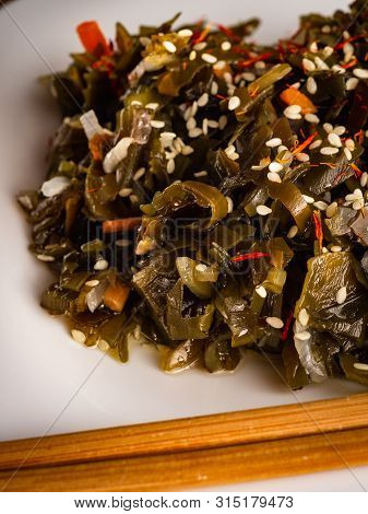 Seaweed Salad With Sesame Seeds Is On A White Plate