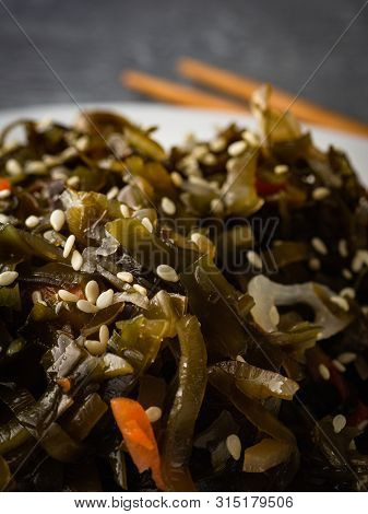 Seaweed Salad With Sesame Seeds Is On A White Plate