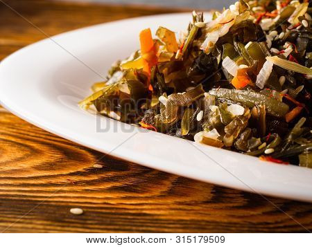 Seaweed Salad With Sesame Seeds Is On A White Plate