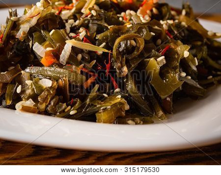 Seaweed Salad With Sesame Seeds Is On A White Plate