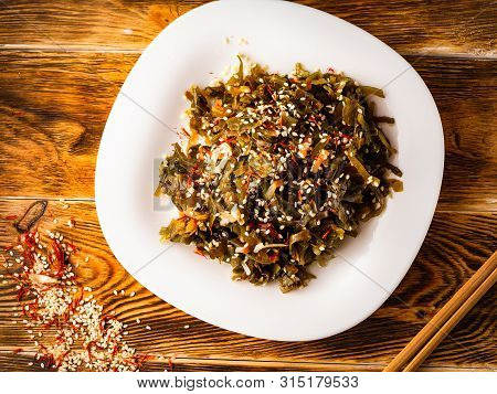 Seaweed Salad With Sesame Seeds Is On A White Plate