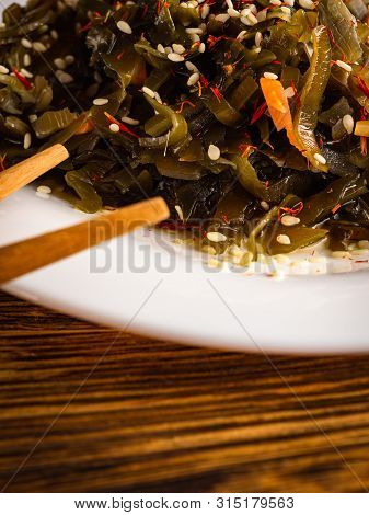 Seaweed Salad With Sesame Seeds Is On A White Plate