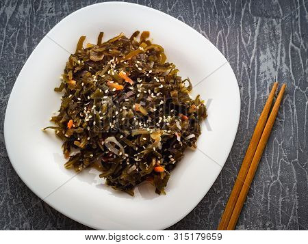 Seaweed Salad With Sesame Seeds Is On A White Plate