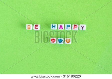 Phrase Be Happy Made Out Of Beads On Bright Green Background