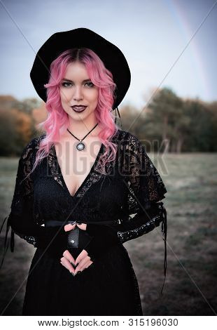 Halloween Theme: Contemporary Cute Young Witch In Black Dress And Hat