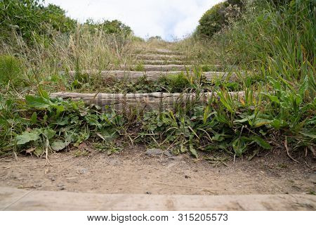Outdoor Stairs On A Dirt Path Overrun With Grass Leading Upward
