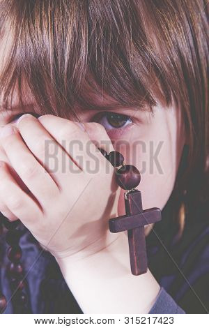 Concept: Developing The Spiritual Life Of Children. Little Child Girl Praying And Holding A Wooden R