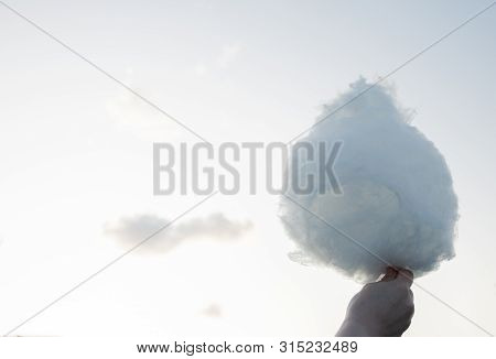 Tangle Of Sweet Cotton Candy Like A Cloud In Your Hand Against The Sky.