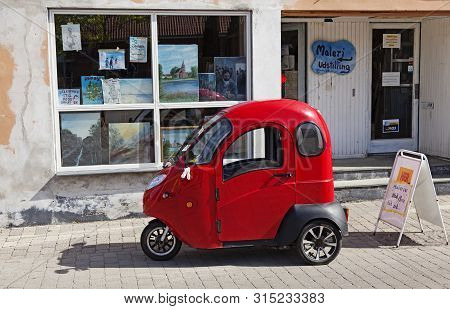Rodby, Denmark - Jun 24, 2019: A Red Three-wheeled Car On The Pedestrian Street