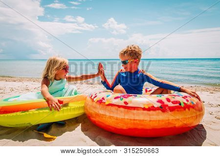 Happy Cute Boy And Girl Play With Floaties On Beach