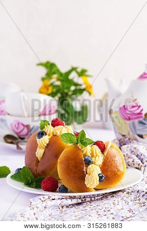Rum Baba Decorated With Whipped Cream And Fresh Raspberry, Blueberry. Savarin With Rum, Cream And Be