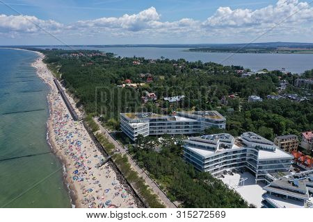 Drone Aerial Perspective View On Sunny Beach With Sunbathers With Windbreaks And Towels At Sea In To