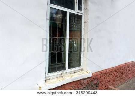Old Aged White Brick Wall With Dirty Window Glasses And Iron Bars With A Black Background.