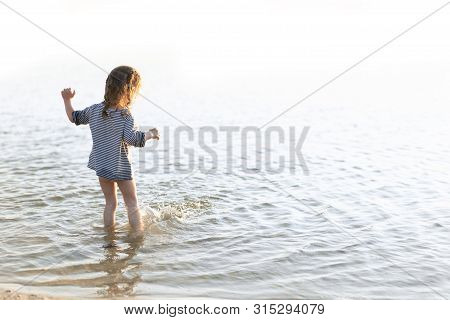 Happy Child Running And Jumping In The Waves During Summer Vacation. Holiday On Sea Or Ocean Coast F