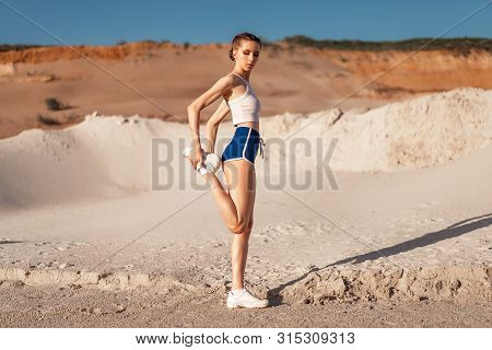 Young Woman Stretching Legs And Warming Up At The Nature. Attractive Girl Stretching Before Fitness.