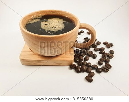 Black coffee in wood cup, coffee beans on old wooden texture background. Selective focus