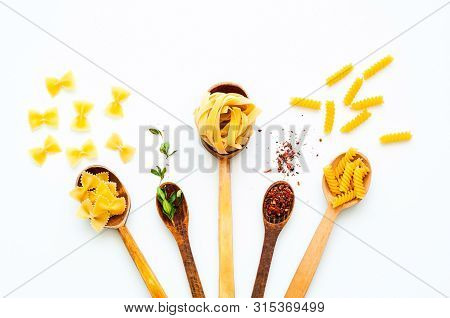 Wooden Spoons With Pasta And Spices On White Isolated Background. The Concept Of Italian Cuisine. Cl