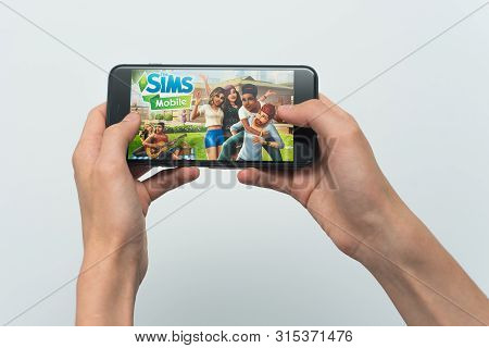 Samara, Russia -07, 29, 2019: A Young Guy Plays A Sims Game On Iphone 8 Plus. Teenage Boy Holding A 