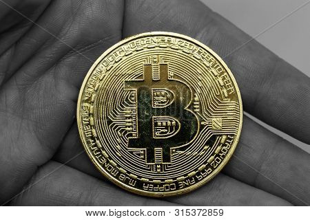Golden Bitcoin In A Man Hand, Digitall Symbol Of A New Virtual Currency With Black And White Backgro