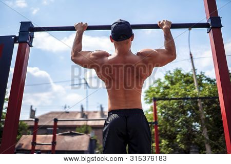 Brutal Athletic Man Making Pull-up Exercises On A Crossbar At Outdoor Streeet Gym.