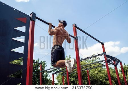 Brutal Athletic Man Making Pull-up Exercises On A Crossbar At Outdoor Streeet Gym.