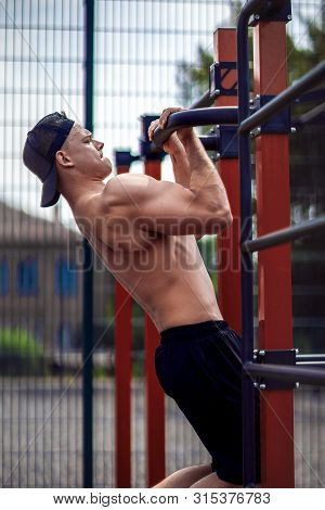 Brutal Athletic Man Making Pull-up Exercises On A Crossbar At Outdoor Streeet Gym.