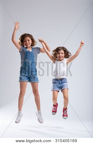 Two Vivacious Lively Little Girls Jumping Together