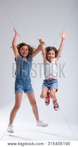 Two Exuberant Hyperactive Young Girls Jumping