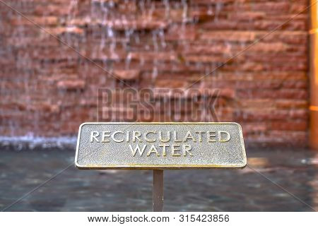 Close Up Of Metal Plate With Words Recirculated Water Embossed On Surface