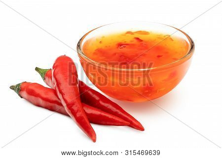 Sweet Chilli Sauce In A Glass Bowl Next To Three Red Chillies Isolated On White.