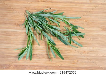 Several Stems Of The Fresh Rosemary, Also Known As Anthos On A Bamboo Wooden Surface