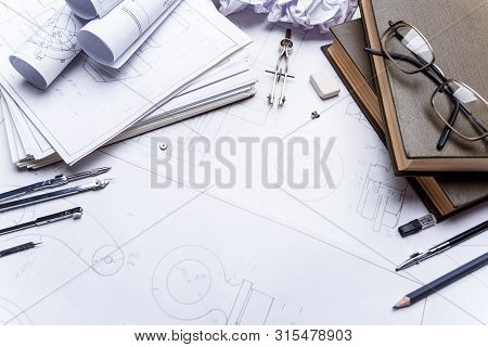 Books, Glasses, Pencil, Compass And Rolls Of Drawings On The Details Of Industrial Drawings