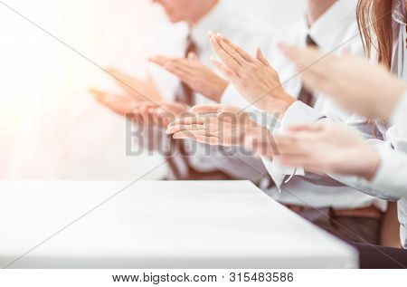 Business Team Applauding Rapporteur At The Desk In The Office