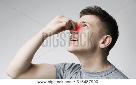 Epistaxis. Young Man Touching His Bleeding Nose, Panorama, Close Up