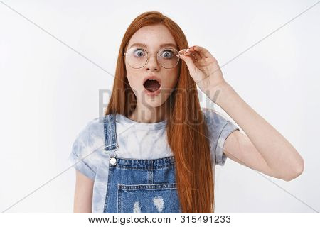 Omg No Way. Impressed Gasping Redhead Girlfriend Drop Jaw Touch Glasses Astonished, Pop Eyes Camera 