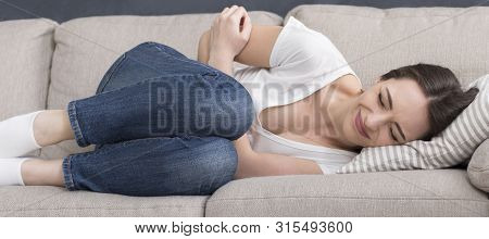Young Lady Laying On Couch At Home And Suffering From Stomach Pain, Panorama