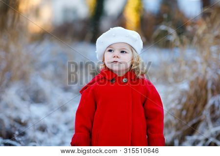 Outdoor Winter Portrait Of Little Cute Toddler Girl In Red Coat And White Fashion Hat Barret. Health