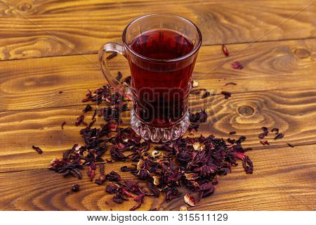 Glass Cup Of Red Hibiscus Tea (carcade, Roselle) On Wooden Table