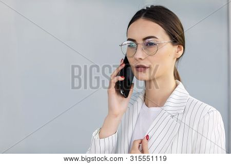 Business Woman With Phone Near Office. Portrait Of Beautiful Smiling Female In Fashion Office Clothe